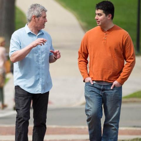 Rob Gallagher walking across campus with student