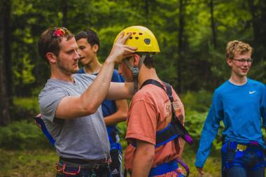 a man helping a child put on rock-climbing helmet and gear