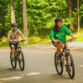 two women bike down HoneyRock road at HoneyRock in Three Lakes, WI