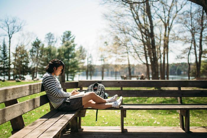 student studies on a deck on Chrouser Lawn at HoneyRock in Three Lakes, WI