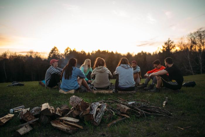 students gather on skill hill around a fire at HoneyRock in Three Lakes, WI