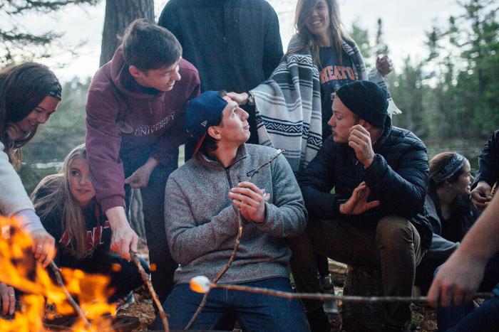 students sitting around campfire at honeyrock in three lakes, wi