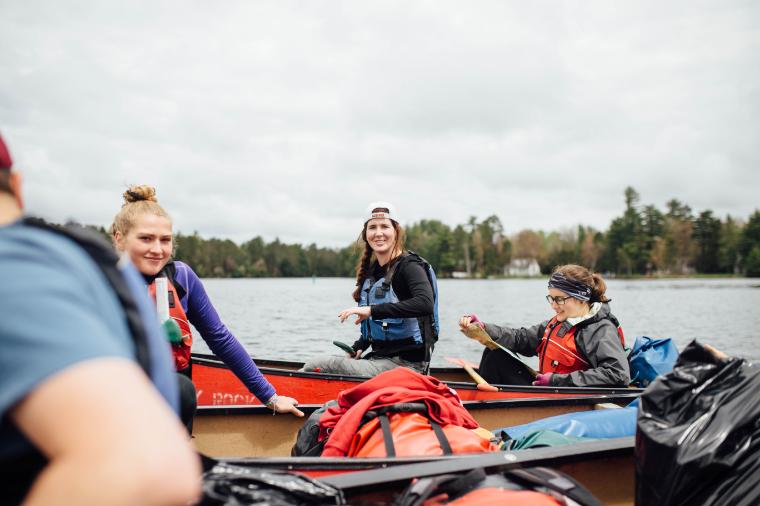 students canoeing on long lake with map