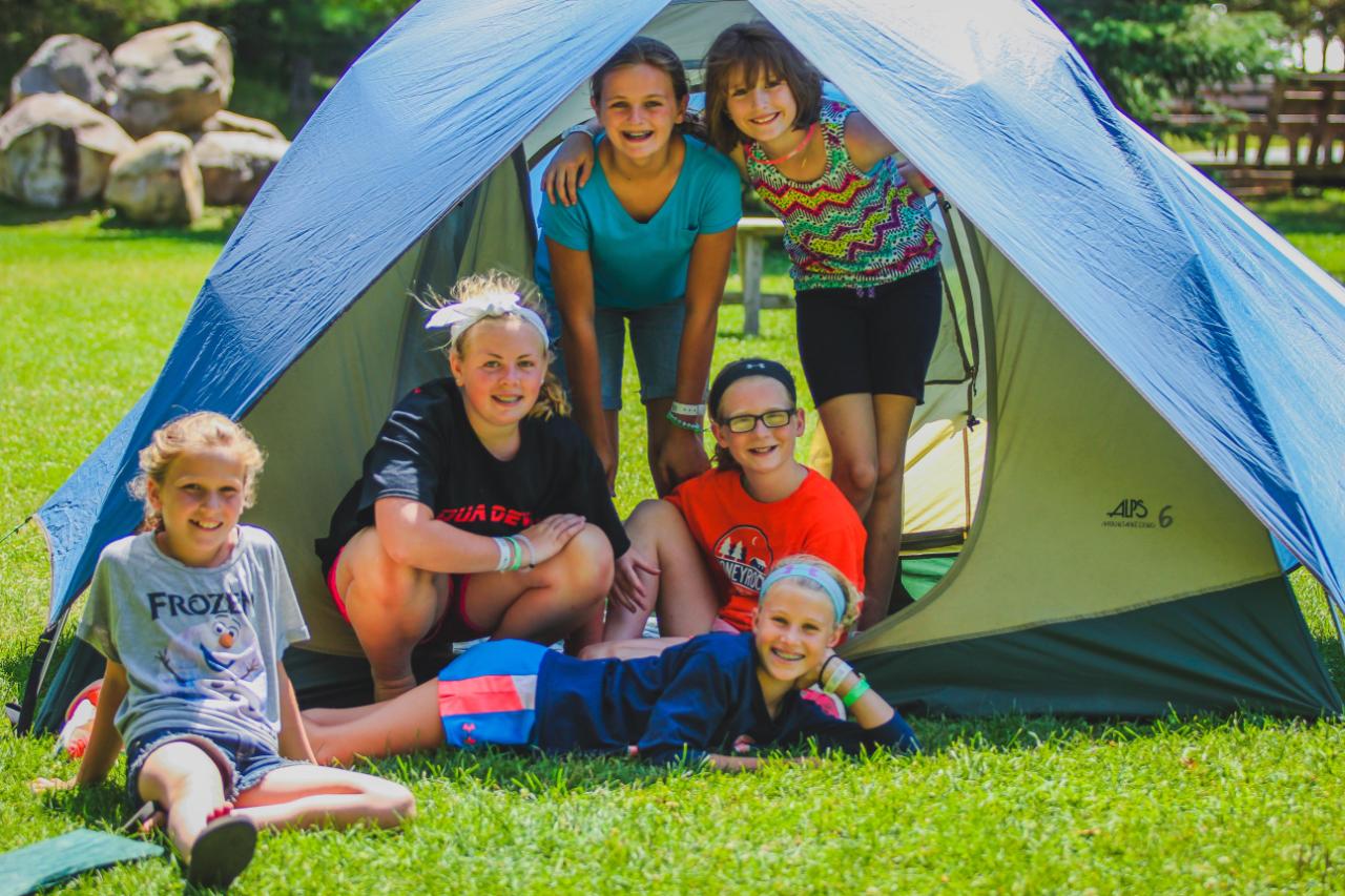 camper girls setting up tent on chrouser lawn at honeyrock in three lakes, wi