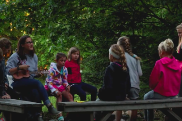 campers sit around the campfire with counselor signing and roasting marshmallows at HoneyRock