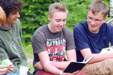 campers and counselor read a journal at HoneyRock in Three Lakes, WI