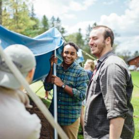 three guys help set up the Blue and White Tent at HoneyRock in Three Lakes, WI