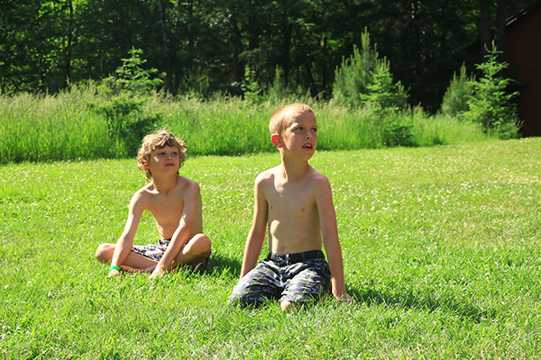 Two boys sitting in grass shirtless