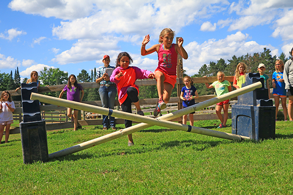 Group of girls jumping over hurdle